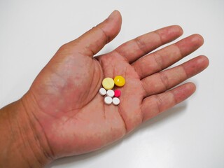 Many tablets are in the left hand on a white background.