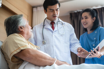 Obraz premium Surgeon doctor with digital tablet visiting senior male patient in hospital bed at geriatric unit