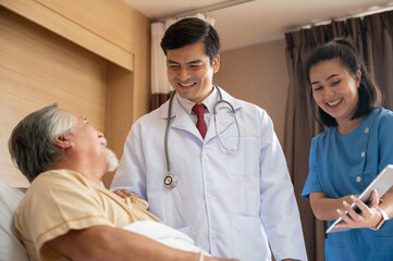 Surgeon doctor with digital tablet visiting senior male patient in hospital bed at geriatric unit