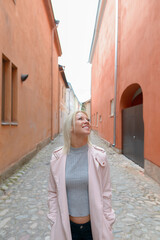 Happy young beautiful blonde woman thinking along the alley