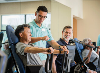 senior man exercising with trainer in gym
