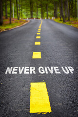 Never give up word on asphalt road surface with marking lines, business success concept and positive challenge emotion idea