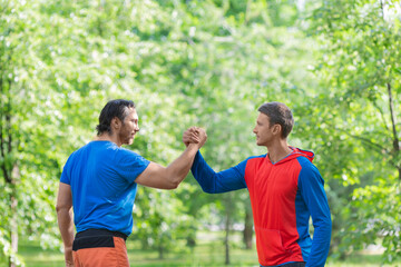 Two men after workout outdoor shake hands.