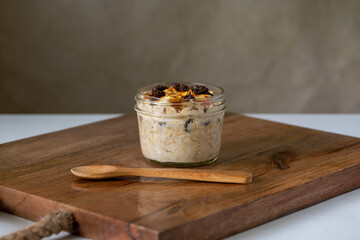 Dried oranges and raisins overnight oats on brown wooden board and a spoon, selective focus ,...