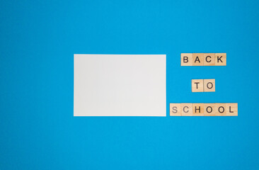 On a blue background, a notebook sheet and a phrase made of wooden letters, back to school, the concept of returning to school after the holidays.
