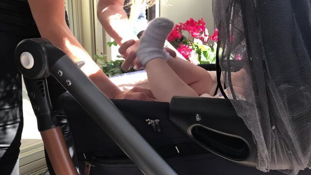 Mother is cleaning a baby bum and changing a baby's diaper in a stroller.