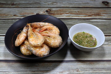 Traditional roasted banana shrimp on the plate serving with spicy dipping sauce. Famous boiled or grilled seafood menu in Asia restaurant. 