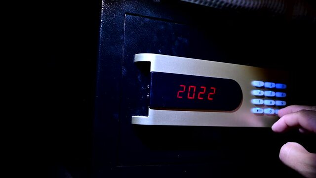 Thief opens the digital safe. Stealing money and valuables at dark night.