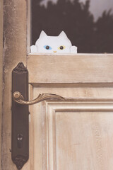 A white paper cat with a blue and a yellow eye sticked on door glass. 