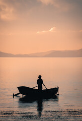 Naklejka na ściany i meble Beautiful vertical landscape with man on a boat during sunset in Lake Titicaca, Island of the Sun, Bolivia