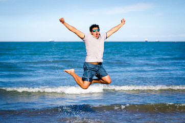 Joven feliz brincando frente al mar azul 