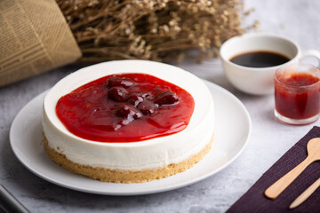 Ice box cheese cake with strawberry jam and a cup of coffee on the table.