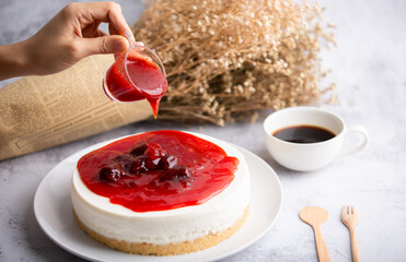 Ice box cheese cake with strawberry jam and a cup of coffee on the table.