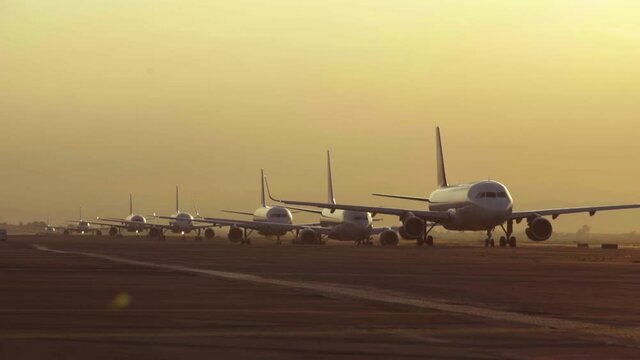 Airplanes lined up on the runway waiting for take of during sunrise