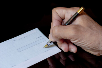 Closeup man hand write and sign checkbook.
