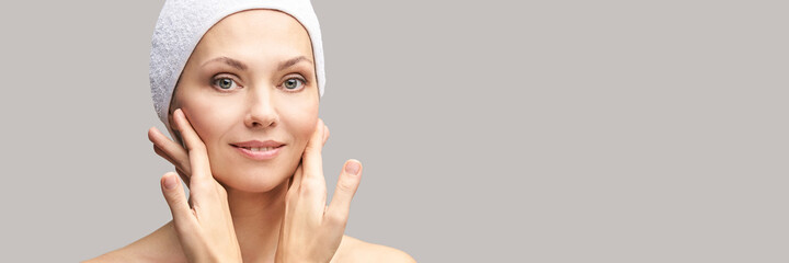 Happy pretty woman. Hands near face. Skincare concept. Home morning routine. Clean skin. Cream cosmetics. Cosmetology therapy. Rejuvenation procedure. Grey background. Copyspace