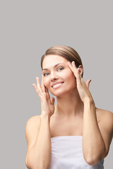 Happy pretty woman. Hands near face. Skincare concept. Home morning routine. Clean skin. Cream cosmetics. Cosmetology therapy. Rejuvenation procedure. Grey background. Copyspace