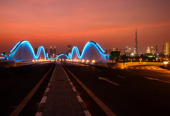Illuminated Meydan bridge and view of Dubai city at dusk