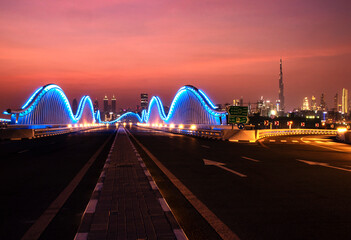 Illuminated Meydan bridge and view of Dubai city at dusk
