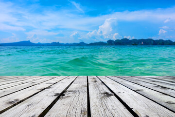 Naklejka na ściany i meble Wooden floor or plank on sand beach in summer. For product display.Calm Sea and Blue Sky Background.