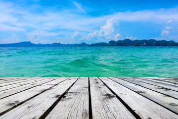 Fototapeta premium Wooden floor or plank on sand beach in summer. For product display.Calm Sea and Blue Sky Background.