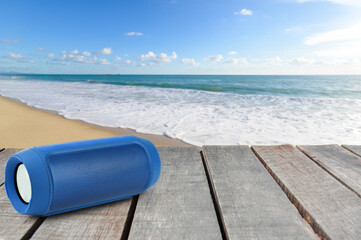 Portable speaker, placed on a wooden floor for a party on the beach.