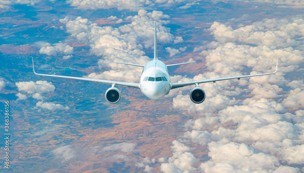 Wall mural white passenger airplane in the clouds - travel by air transport