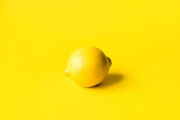 One ripe lemon on a yellow background. Monochrome image. Minimal summer concept.