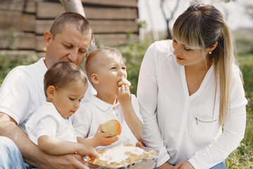 Family with cute little children. Father in a white shirt. People have a picnic on a yard.