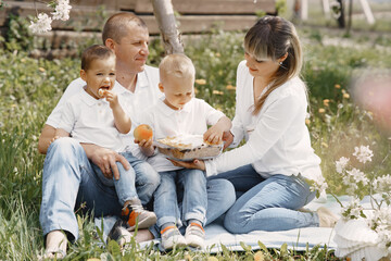 Family with cute little children. Father in a white shirt. People have a picnic on a yard.