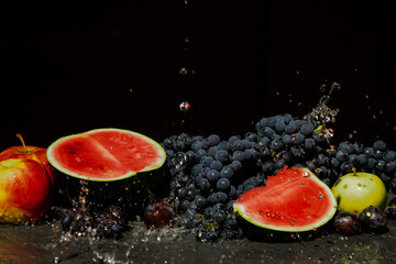 watermelon, grapes, plums and apples in a spray of water