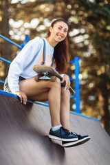 Girl is resting with a skateboard in her hands before skating