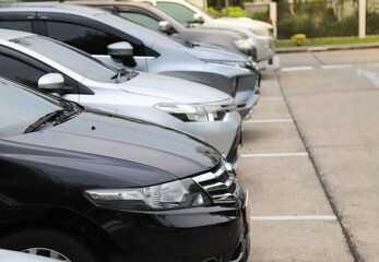 Closeup of front side of black car with other cars parking in outdoor parking area.