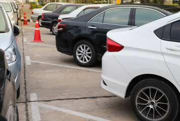 Closeup of rear, back side of white car with  other cars parking in outdoor parking area.