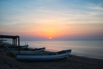 Muscat, Oman. Circa June 2020. A beautiful sunset along a calm beach lined with fishermen's boats.