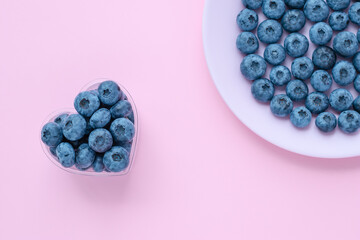 Blueberries in a heart shaped bowl, berry on a pink plate, dish. Abstract backgrounds, bright summer wallpaper. Selective focus.