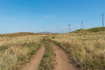 Fototapeta na wymiar Summer steppe landscape. Landscape in kazakhstan. Kazakh steppe. Power line. Blue sky. Yellow grass. Panorama. Country road