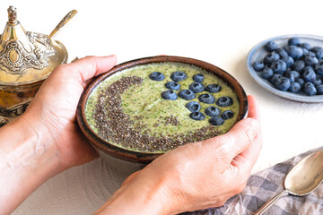 Celery banana smoothie with Chia seeds and fresh blueberries close up on white background. Woman serving breakfast