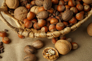 nuts in a basket. beautiful still life close-up on a dark background. Walnut, hazelnuts (hazel), pine nuts, pecans, pine cones.