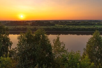 Beautiful views of the sunset over the river with trees, fields and flowers