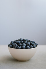 Freshly picked blueberry in white bowl on dark blue background. Handful of sweet ripe berries close up 