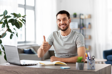 technology, remote job and business concept - happy smiling man with laptop computer showing thumbs up at home office