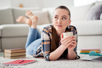 Closeup photo of beautiful young lady student lying floor clever person hold hot coffee cup look up dreamer good mood social distance quarantine time stay home indoors