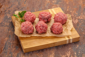 Raw meatball over wooden background