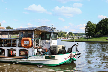 Fototapeta na wymiar KRAKOW, POLAND - JULY 14, 2020: Barges and ships on Wisla river near Wawel Royal Castle