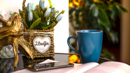 Evening coffee. Blue cup with coffee, open book and mobile phone, evening light, sunset, dusk. Atmospheric, cozy evening in the garden, green leaves, conversation. Warm light, blur bokeh.