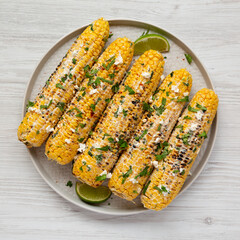 Homemade Elote Mexican Street Corn on a plate on a white wooden table, top view. Flat lay, overhead, from above.