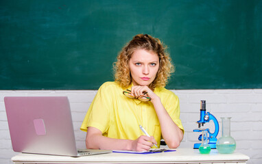 Pharmacy. biology experiment research. serious student with microscope and beaker. make notes about...