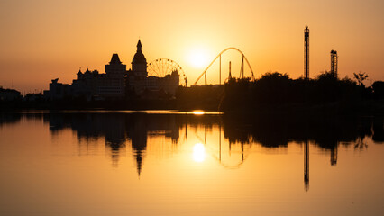 Naklejka premium Sunset over the water. The silhouette of the building. The amusement park. Shadows. Sochi Park. No focus. Blur