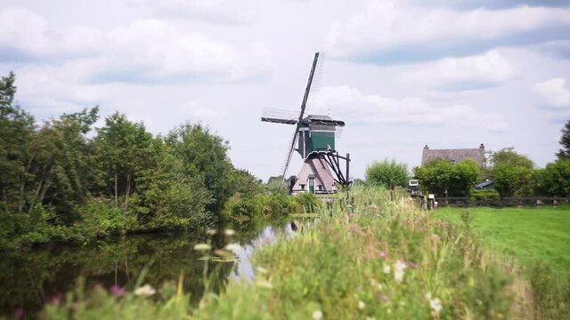 4k Windmill Oukoopse Molen standing in typical Dutch nature near channel.
